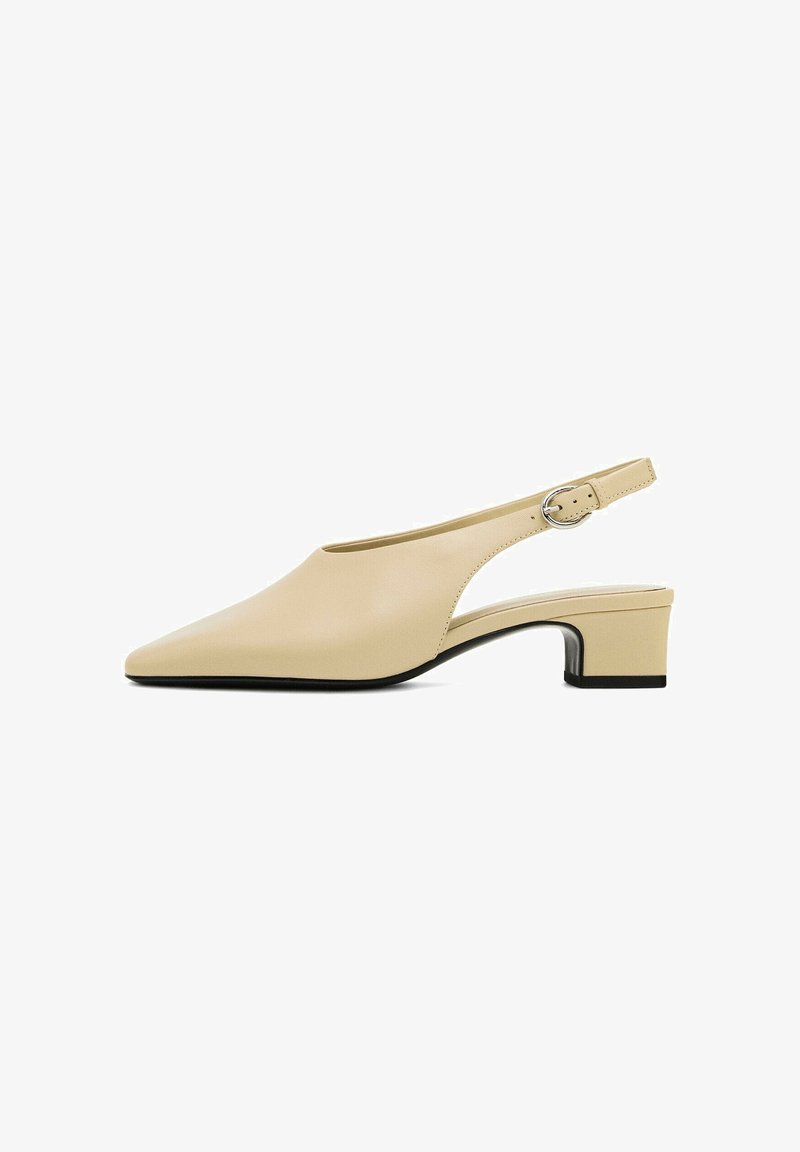 Chaussure slingback en cuir beige avec un bout pointu, un petit talon bloc et une boucle circulaire sur la sangle ajustable. Texture lisse.