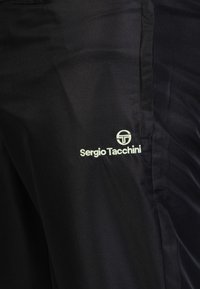 Schwarze Sportshorts aus strukturiertem Stoff. Mit einem weißen Logo "Sergio Tacchini" auf der unteren linken Seite.