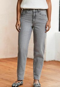 Grau hochtaillierte Jeans aus Denim mit geradem Schnitt. Auffällig durch das klassische Fünf-Taschen-Design und dezente Ausbleichungen. Flache schwarz-weiße gestreifte Schuhe.