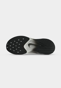 Μαύρη και λευκή σόλα παπουτσιού Nike με υφασμένο μοτίβο κράτησης και κεντρικό λογότυπο Nike swoosh σε καθαρό λευκό φόντο.