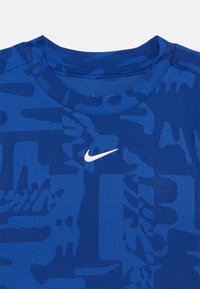 Blå sports T-shirt med et struktureret mønster. Har en rund halsudskæring og et hvidt Nike-logo på brystet. Lavet af åndbart stof.
