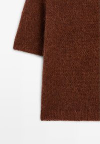 Bruine gebreide trui stof met een zachte, fuzzy textuur. Heeft korte mouwen en een relaxed fit. Geen zichtbare patronen of hardware.
