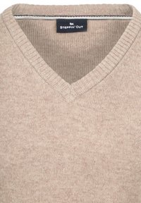 Beiger V-Ausschnitt-Pullover aus weichem Strickstoff mit geripptem Kragen und Struktur. Mit einem Etikett mit der Marke "STEPPIN' OUT" innen.