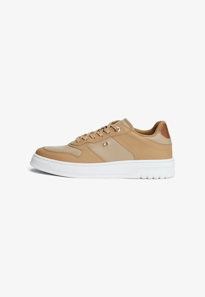 Sneaker in pelle beige con una texture liscia, suola in gomma bianca e design con lacci. Presenta delle perforazioni sottili e un dettaglio con logo sul lato.