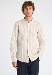 Camicia a righe chiara con colletto a fascia, maniche lunghe, chiusura a bottoni e orlo dritto. Il tessuto appare liscio e simile al cotone.
