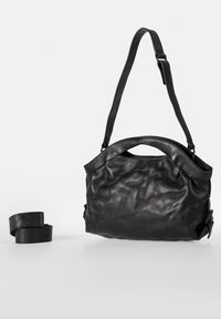 Zwarte leren handtas met een zachte, gekreukte textuur, korte handgreep en verstelbare schouderband. Voorzien van een klemming en minimale hardware.