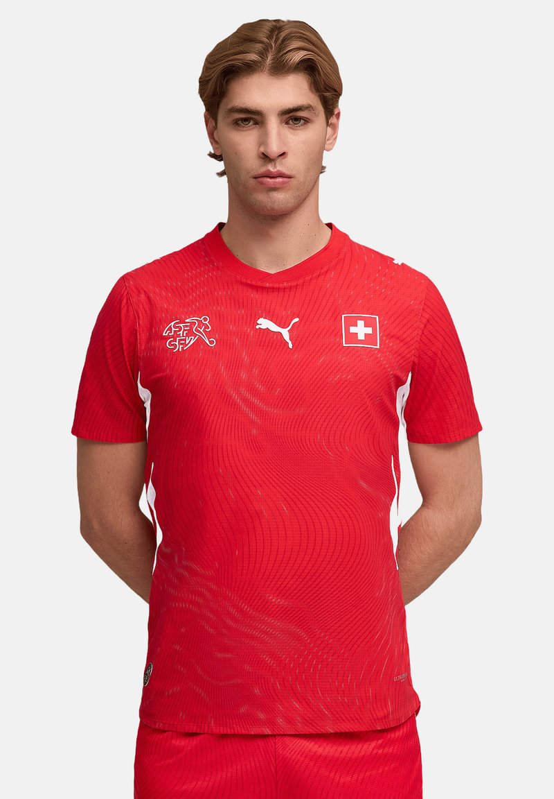 Rotes Fußballtrikot mit kurzen Ärmeln, Wellendesign, weißen Akzenten, Schweizer Flagge, Puma-Logo und Rundhalsausschnitt.