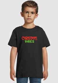 Sort bomulds t-shirt med "CHRISTMAS VIBES" i røde og grønne bogstaver, med festlige træikoner, rund halsudskæring og korte ærmer.
