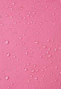 Różowa teksturowana powierzchnia z rozproszonymi kroplami wody, podkreślająca jej gładki i lekko wypukły wzór.