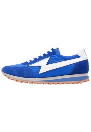 Blue athletic sneaker with white lightning bolt design, white laces, and gum rubber sole, shown in side profile on white background.