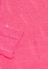 Maglione lavorato a maglia rosa con un motivo testurizzato, polsini a coste e dettagli leggermente sfilacciati, che mette in risalto un tessuto morbido e leggero.