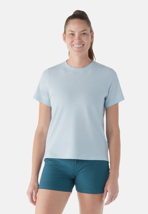 Ljusblå bomulls t-shirt med korta ärmar, rund halsringning och en avslappnad passform, i kombination med mörk teal sportshorts. Enkelt design.