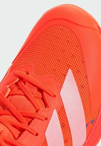 Neon orange athletic shoe featuring a textured mesh upper, smooth synthetic accents, and reflective white stripes. Laces are also orange.