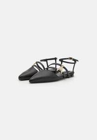 Black leather flats with pointed toes, featuring thin ankle straps and gold hardware accents, textured design, and flat soles.