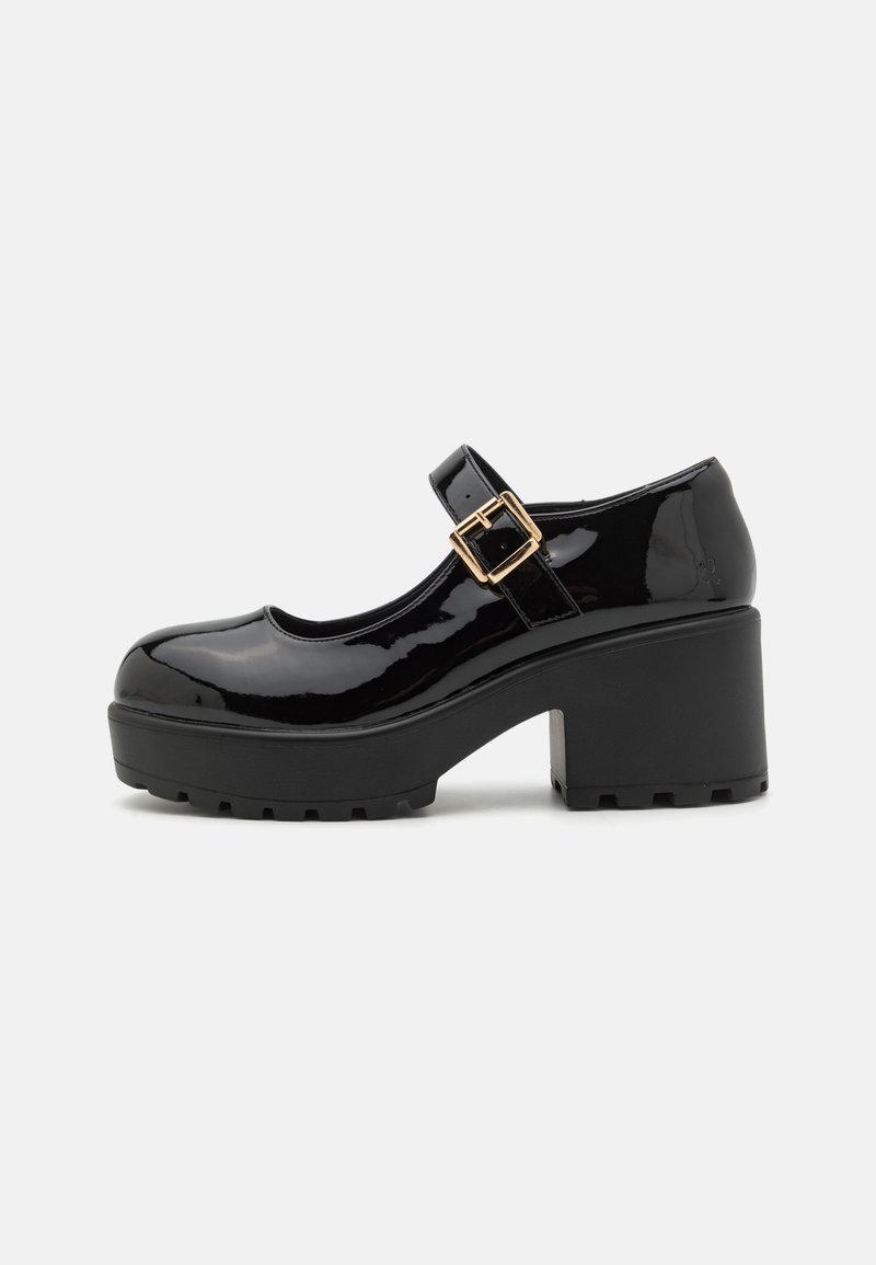 Sapatos Mary Jane de couro envernizado preto com um salto plataforma grosso e texturizado, e uma fivela metálica decorativa na tira.