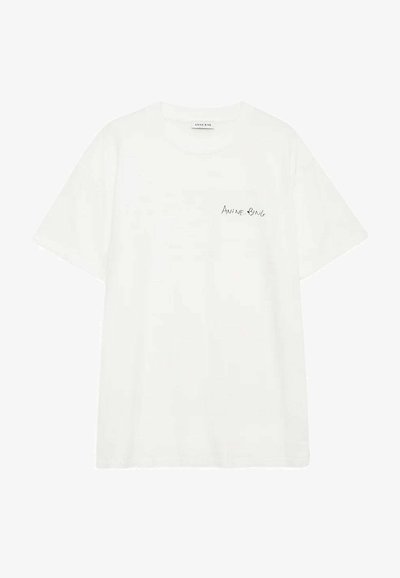 T-shirt en coton blanc avec un col rond et des manches courtes, arborant un petit logo noir "ANINE BING" sur la zone de la poche gauche de la poitrine.