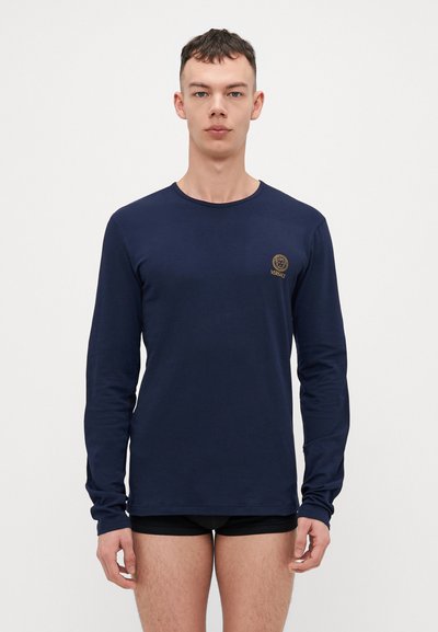 T-shirt à manches longues marine en coton doux, avec un col rond et un logo brodé en doré sur la poitrine gauche.