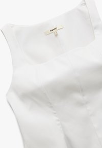 Witte mouwloze jurk met een vierkante halslijn, gemaakt van een soepel weefsel. Beschikt over eenvoudige naden en een waslabel aan de achterkant.