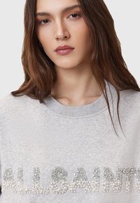 Grijze sweatshirt met de merknaam "ALLSAINTS" versierd met zilverkleurige kralen en stenen, ronde halslijn en zachte textuur.