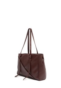 Brown leather tote bag with diagonal seams, two adjustable straps, and a soft texture, featuring a rectangular shape and minimalist design.