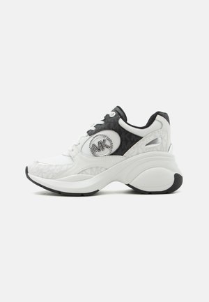 Baskets épaisses blanches et noires avec semelle épaisse, dessus en mesh et cuir, et logo métallique circulaire sur la partie latérale.