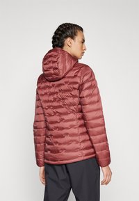 Maroon puffer jacket with a hood, featuring a quilted design and a smooth texture. The back shows elastic cuffs and a fitted silhouette.