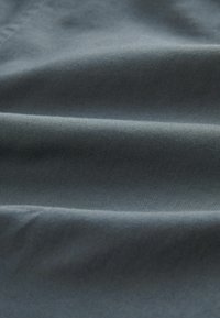 Textile de couleur gris foncé uni avec une texture lisse, présentant des plis doux et une légère brillance. Aucun motif ni accent distinct visible.