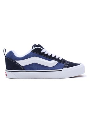 Navy blue suede sneakers with white side stripe, white laces, and a white rubber sole. Features a smooth texture and reinforced heel tab.