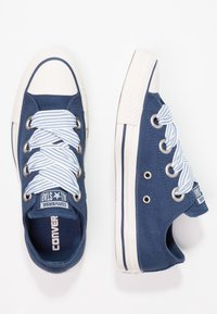 Baskets en toile marine avec semelles en caoutchouc blanc, lacets rayés bleu clair, bout arrondi et logo All Star sur la languette.