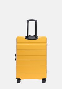 Žlutý tvrdý kufr s horizontálními rýhami, černou rukojetí a čtyřmi kolečky. Kompaktní design s horním madlem a bočním zipem.