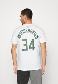 Hvid bomulds T-shirt med "ANTETOKOUNMPO" i grøn skrift over nummer "34," med et NBA-logo på bagsiden.