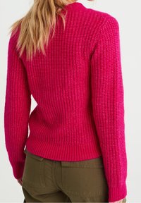 Tajt rosa tröja med en strukturerad ribbad design, långa ärmar och rund halsringning, kombinerad med olivgröna byxor.