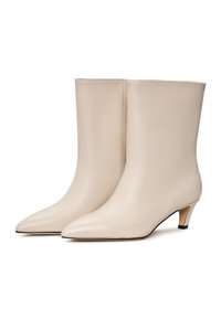 Botine din piele bej, până la gleznă, cu vârf ascuțit și un toc mic. Textură netedă, cu cusături minime, având o siluetă modernă și elegantă.
