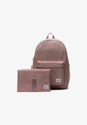 Sac à dos mauve avec une poche zippée à l'avant et une pochette rectangulaire assortie, tous deux ornés d'étiquettes blanches de la marque sur fond blanc.