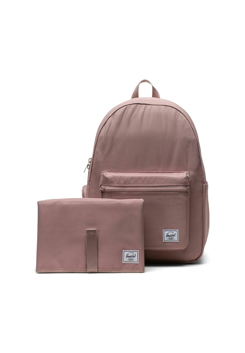 Sac à dos mauve avec une poche zippée à l'avant et une pochette rectangulaire assortie, tous deux ornés d'étiquettes blanches de la marque sur fond blanc.