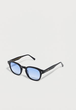 Black square-frame sunglasses with blue gradient lenses resting on a white surface, showing a subtle brand engraving on the temples.