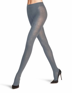 Collant grigi opachi con una superficie liscia e un delicato motivo a coste, che arrivano fino alle caviglie, indossati con scarpe nere con tacco alto.