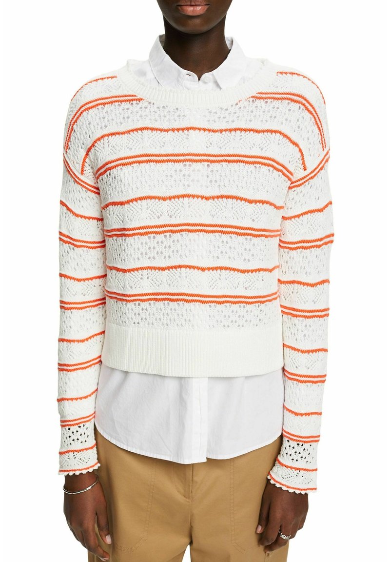 Pull blanc en maille avec des rayures orange, présentant un design court, un tissu texturé et des motifs complexes en dentelle sur les manches.