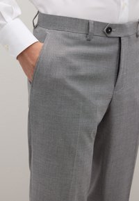 Grijze op maat gemaakte broek van een gladde, gestructureerde stof, met schuine zijzakken en een standaard tailleband met knoopsluiting.