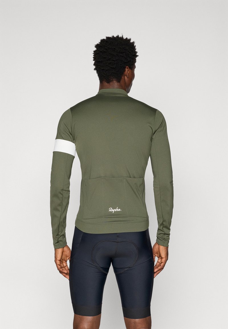 Olivgrön långärmad cykeltröja med vitt ärmsband, med en bakficka och "Rapha"-logotyp vid fållen, matchad med mörka shorts.