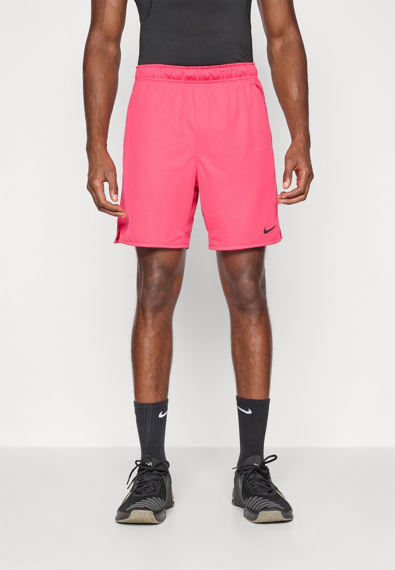 Rosa trening shorts med elastisk midje, sidelommer og en liten svart logo. Brukes med svarte treningssko og sokker.