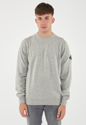 Maglione grigio chiaro con scollo rotondo, maniche lunghe, polsini e orlo a coste, e una patches con logo sulla spalla sinistra. Tessuto morbido e testurizzato.