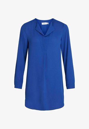 Blauw overhemd met lange mouwen, gemaakt van gladde stof met een puntige kraag en een subtiele plooi aan de voorkant. Afgeronde zoom, gecombineerd met een zwarte broek en laarzen.