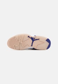 Podeszwa sneakersów wykonana jest z beżowej gumy z purpurowym akcentem oraz okrągłymi wzorami antypoślizgowymi. Wyraźne logo Jumpman w kolorze niebieskim.