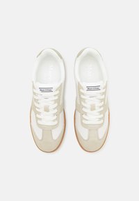 Paire de baskets Marc O’Polo blanches et beiges avec lacets blancs et semelles en gomme, vues de dessus sur un fond uni.