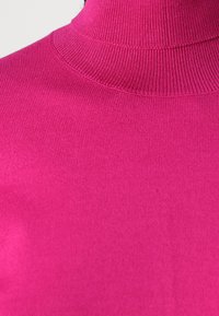 Roze coltrui, geribbelde textuur, close-up uitzicht dat de gladde stof en het detail van de hoge hals benadrukt.