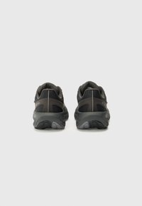 Des chaussures de sport noires avec une tige synthétique lisse, des accents en maille, des semelles rembourrées et des détails réfléchissants sur le talon et les côtés.