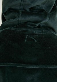 Tmavě zelená fleece mikina s jemnou texturou, disponující složenou kapucí a viditelnými švy, která ukazuje volnočasový design.