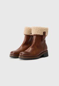 Brązowe skórzane botki za kostkę z beżowym kołnierzem z fleece, z okrągłym noskiem i teksturowaną czarną gumową podeszwą.