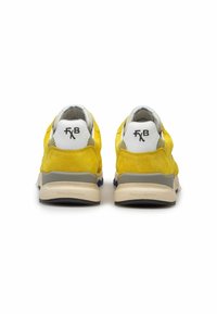 Sneaker gialli in suede con rete e suole bianche a contrasto, viste da dietro, presentano il marchio sul tallone.